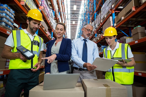 Warehouse manager and client interacting with co-workers in warehouse